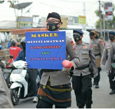 DENGAN MENGGUNAKAN PAKAIAN ADAT, SATBRIMOB POLDA JATIM BAGIKAN 3000 MASKER SECARA GRATIS